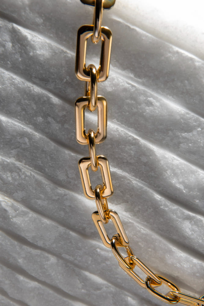 Polished gold link chain on white marble