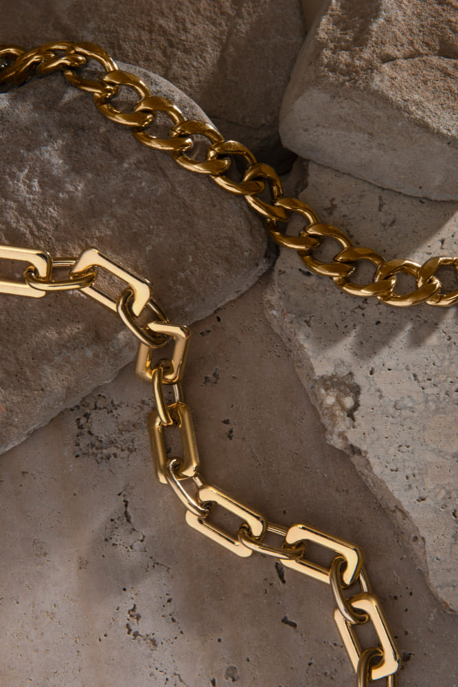 Handcrafted gold chains resting on natural stone